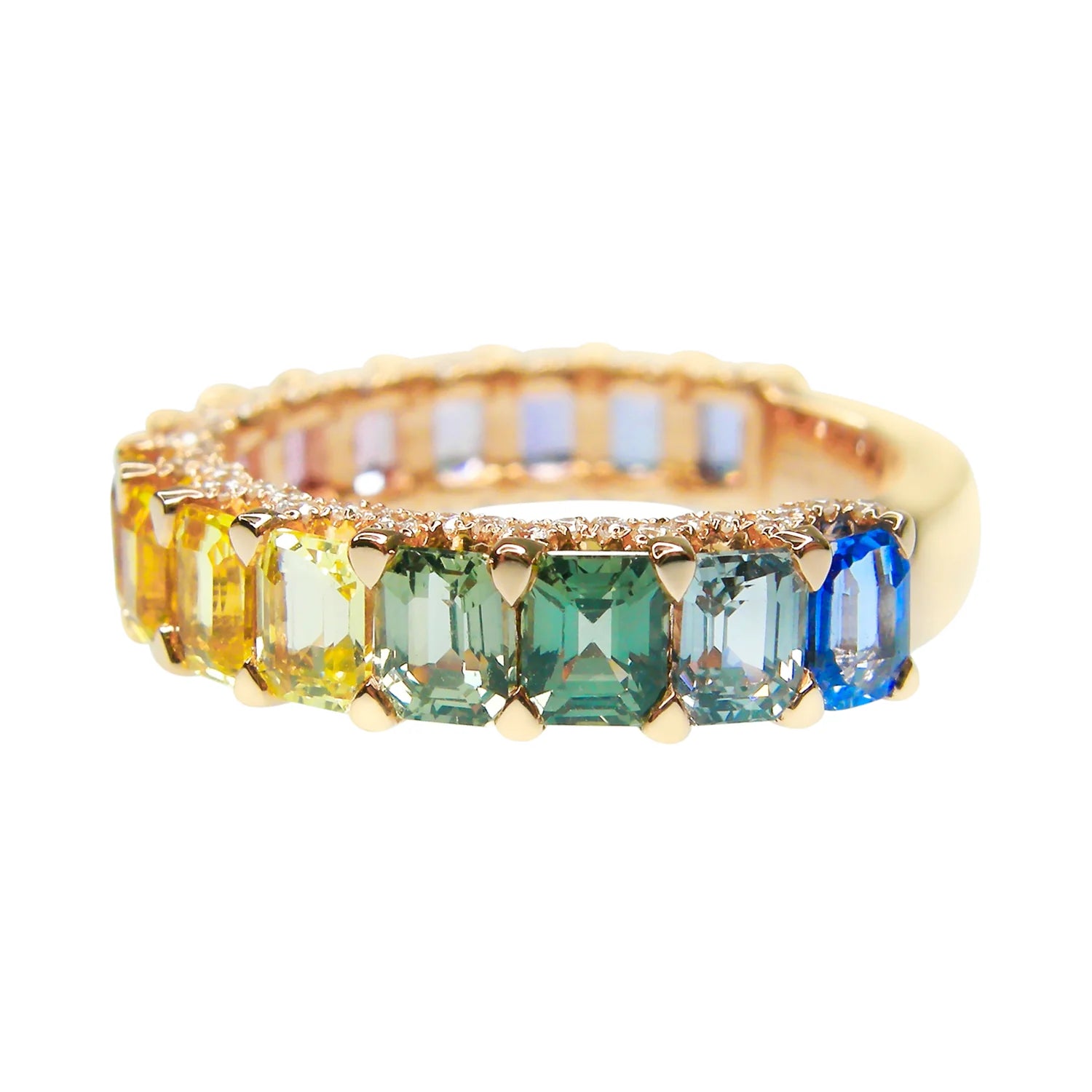 Gold ring with green and blue gemstones on a white background