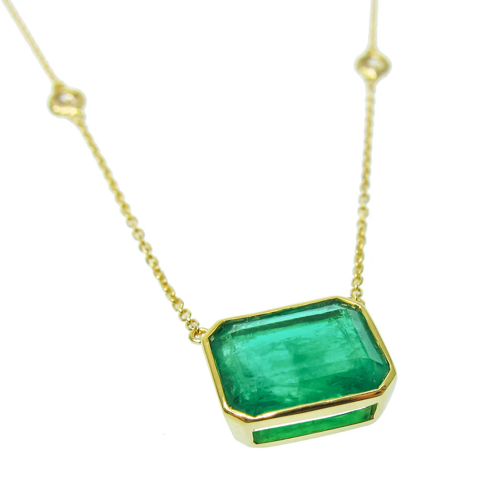 Gold necklace with a green gemstone pendant on a white background