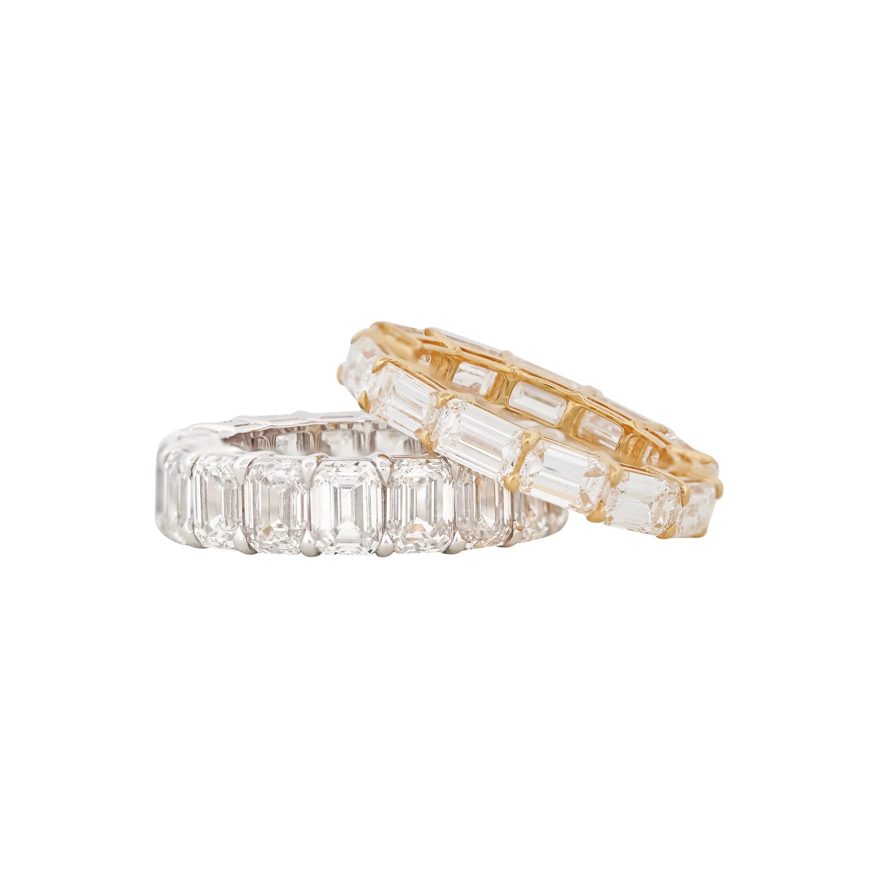 Two diamond eternity rings, one gold and one silver, on a white background.