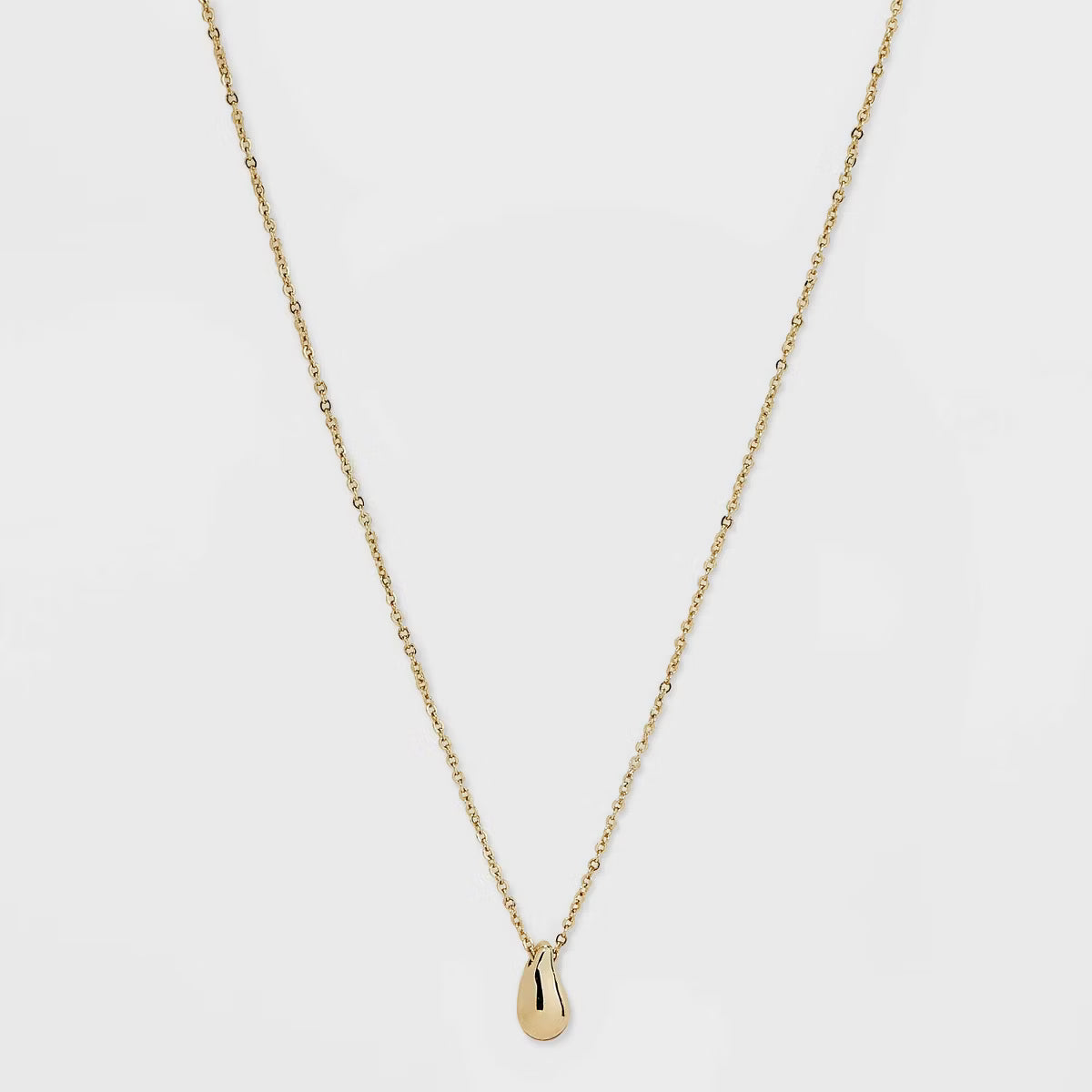 Gold necklace with a small pendant on a light gray background