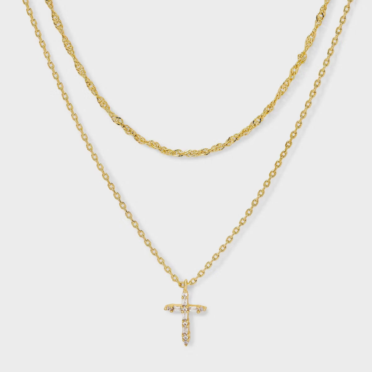 Gold necklace with a cross pendant on a light gray background