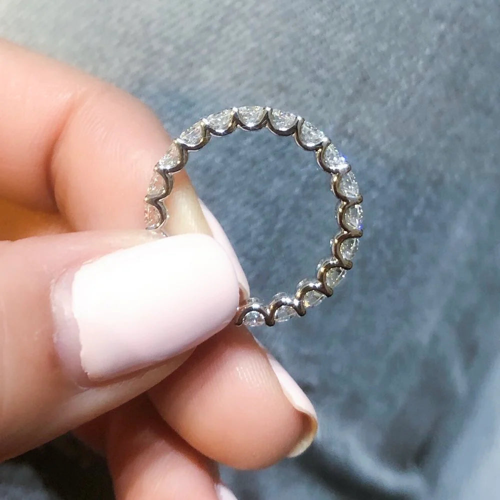 Diamond ring held between fingers against a neutral background