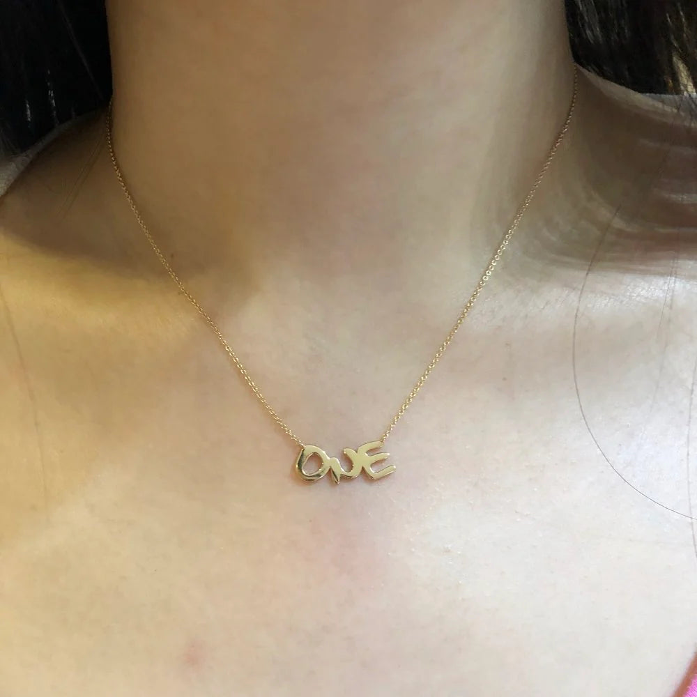 Gold 'LOVE' necklace on a person's neck