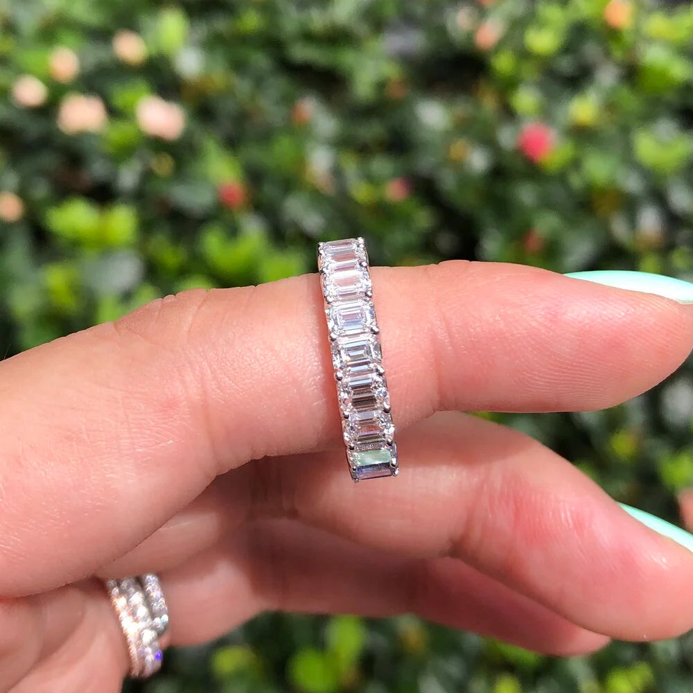 Emerald cut rainbow sapphire and diamond eternity ring on a hand
