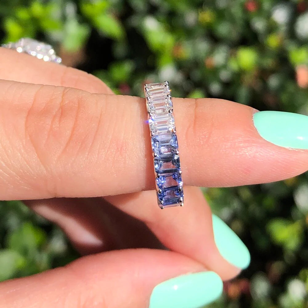 Close-up of rainbow pastel sapphires and emerald cut diamonds in eternity ring