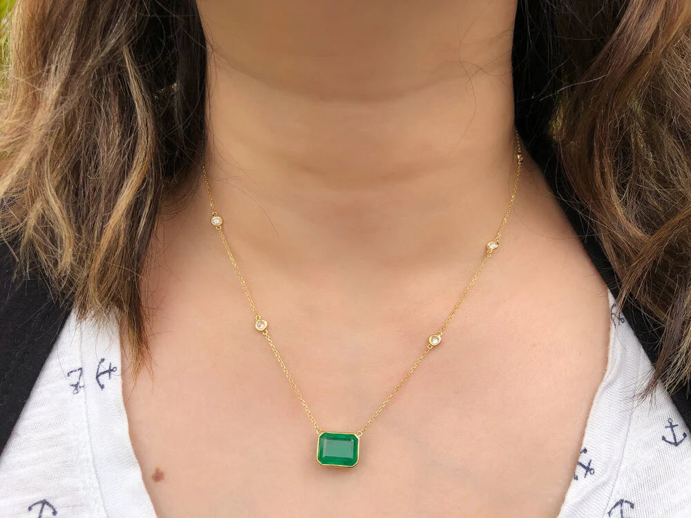 Gold necklace with a green pendant worn by a person