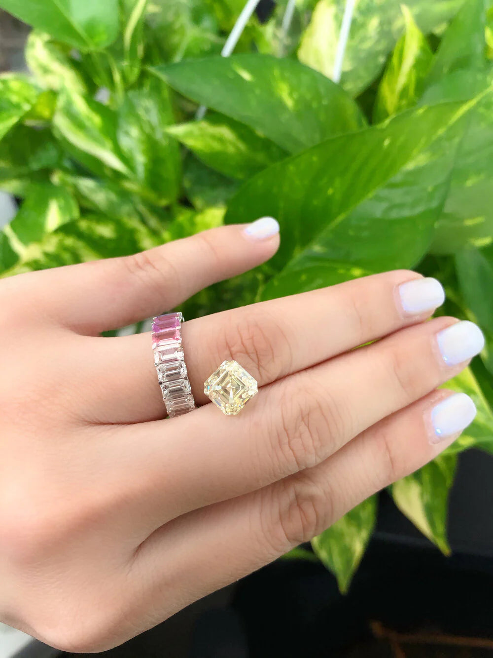 Close-up of rainbow pastel sapphires and emerald cut diamonds in eternity ring