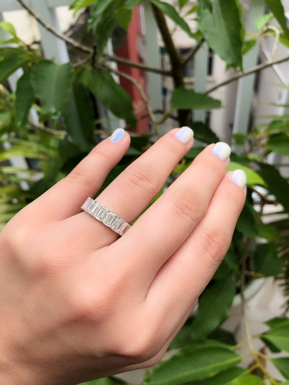Close-up of rainbow pastel sapphires and emerald cut diamonds in eternity ring