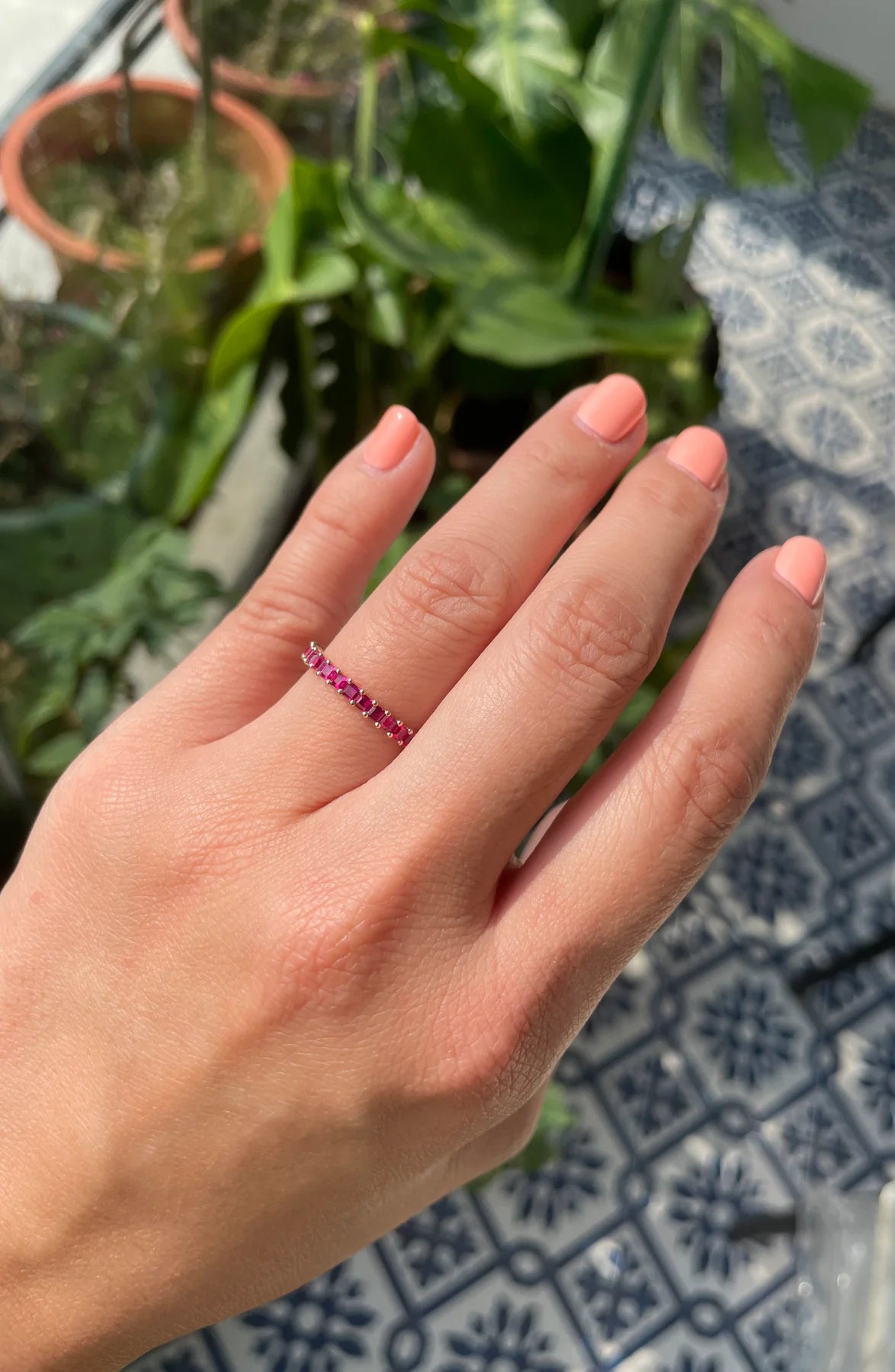 Hand wearing a pink ring with a patterned background