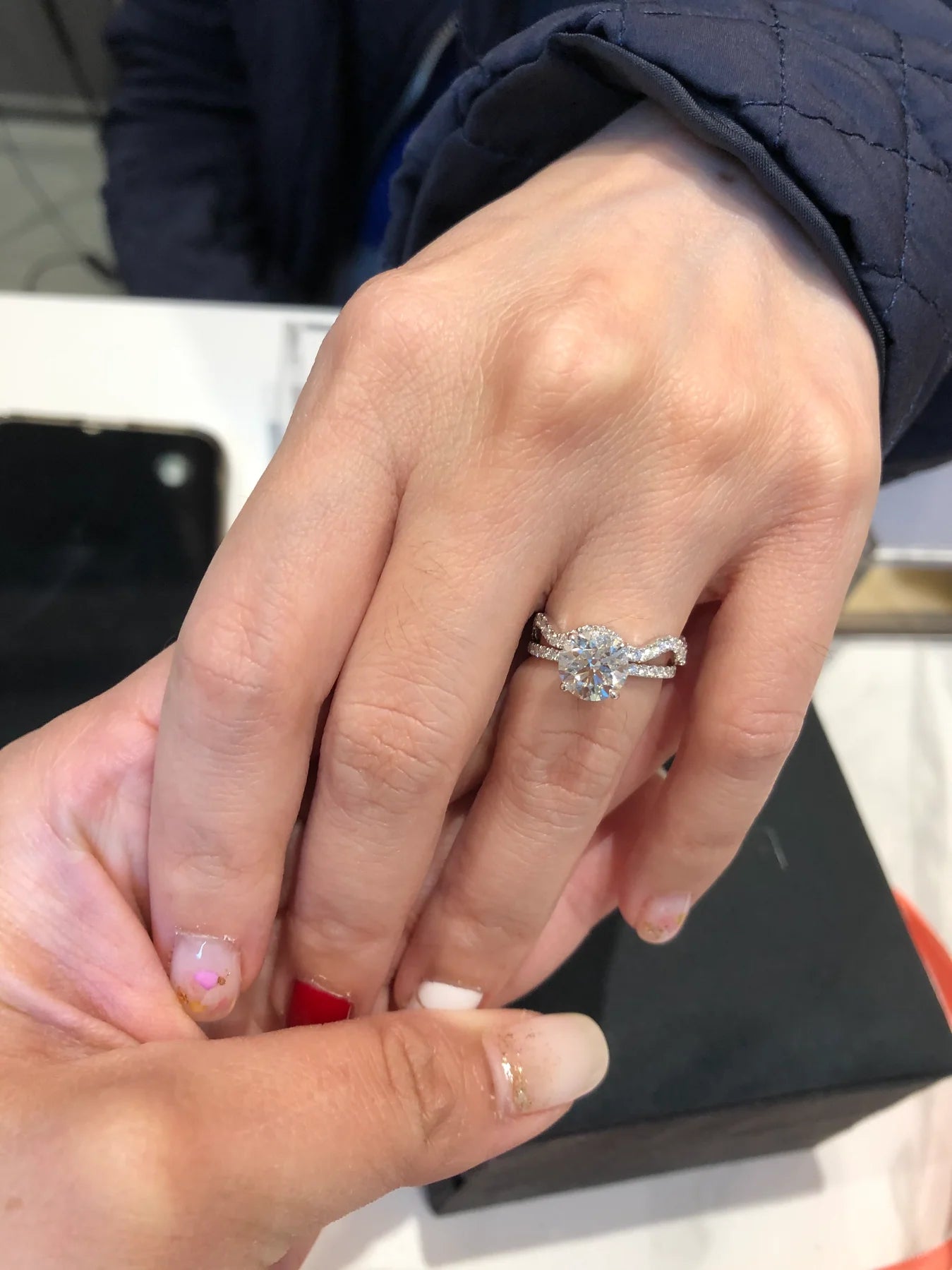 Close-up of a hand wearing an engagement ring with a blurred background