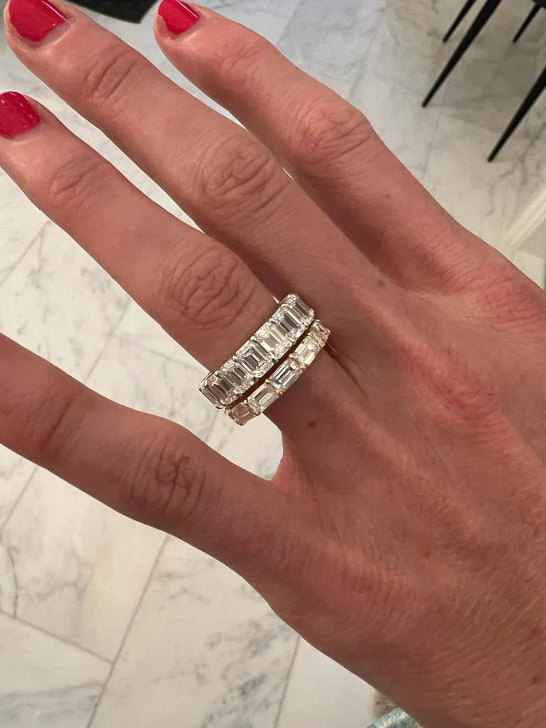 Horizontal emerald cut diamond eternity ring stacked with an engagement ring
