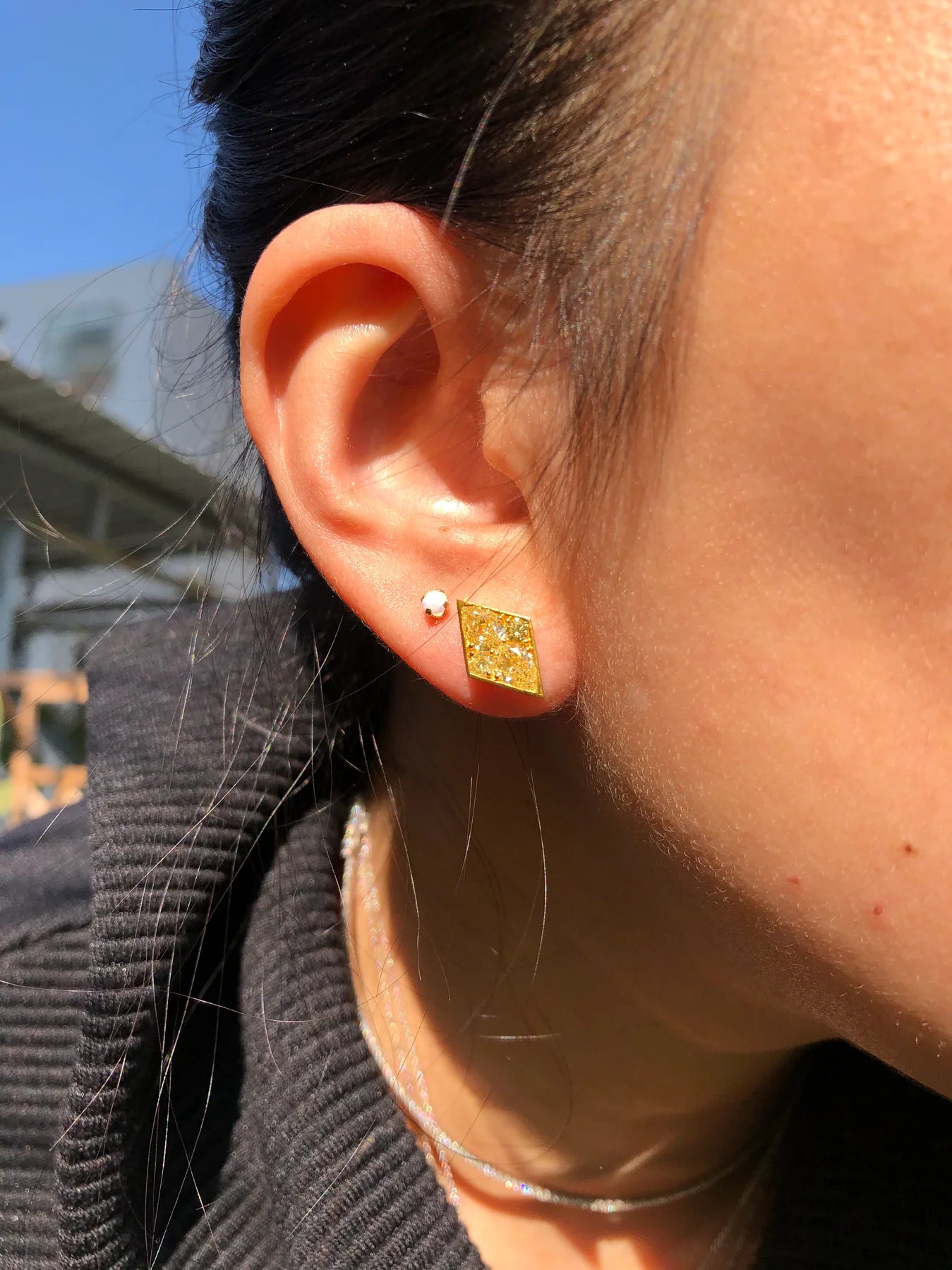 Close-up of an ear wearing a gold earring with a blurred background