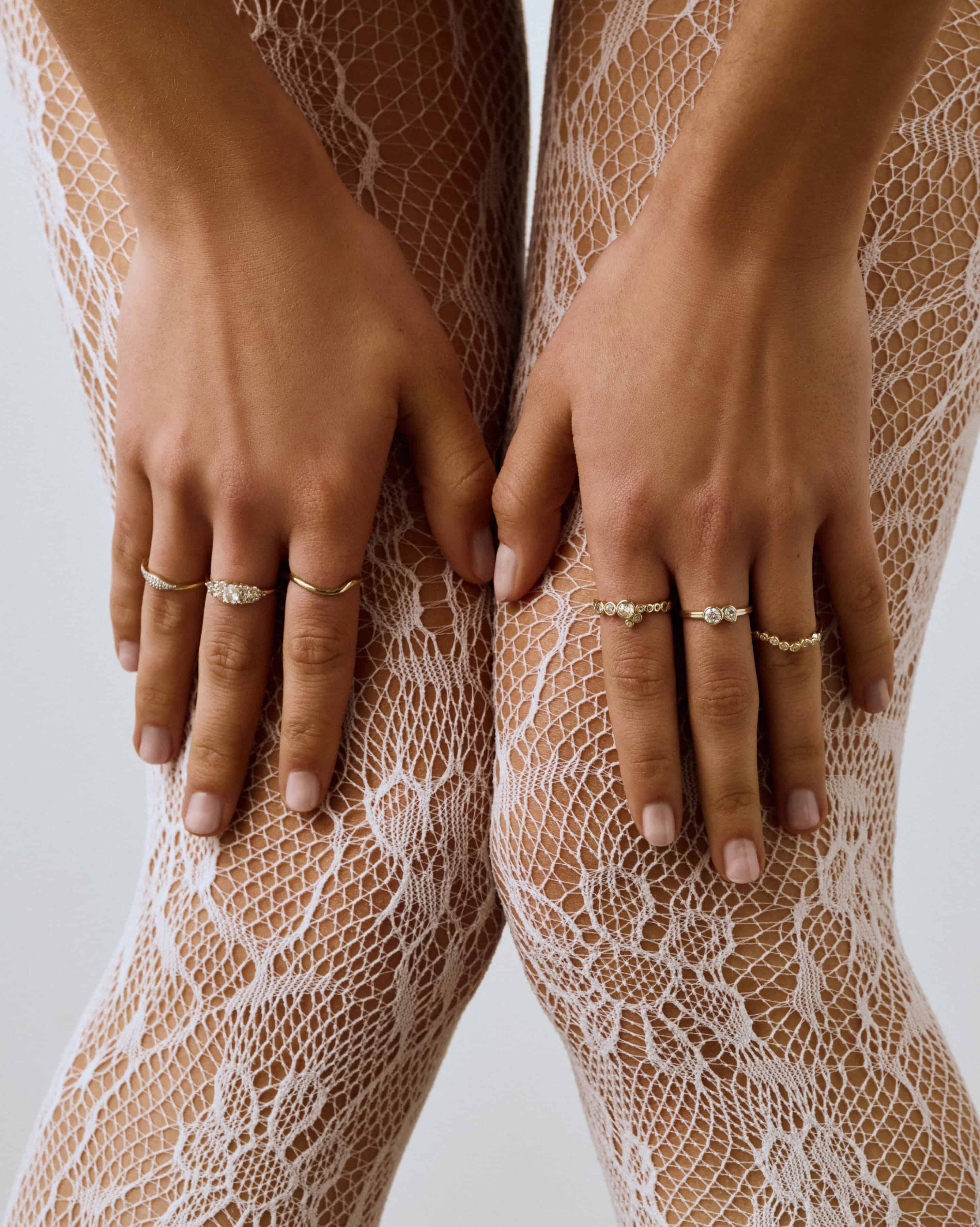 Close-up of hands wearing gold rings on a textured beige background