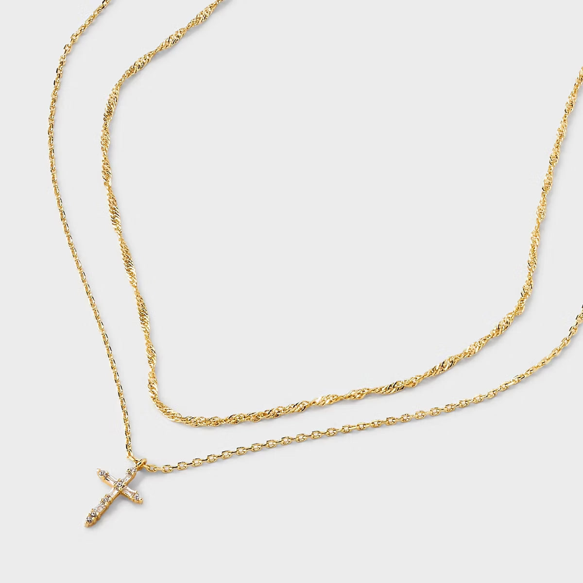 Gold necklace with a cross pendant on a light gray background