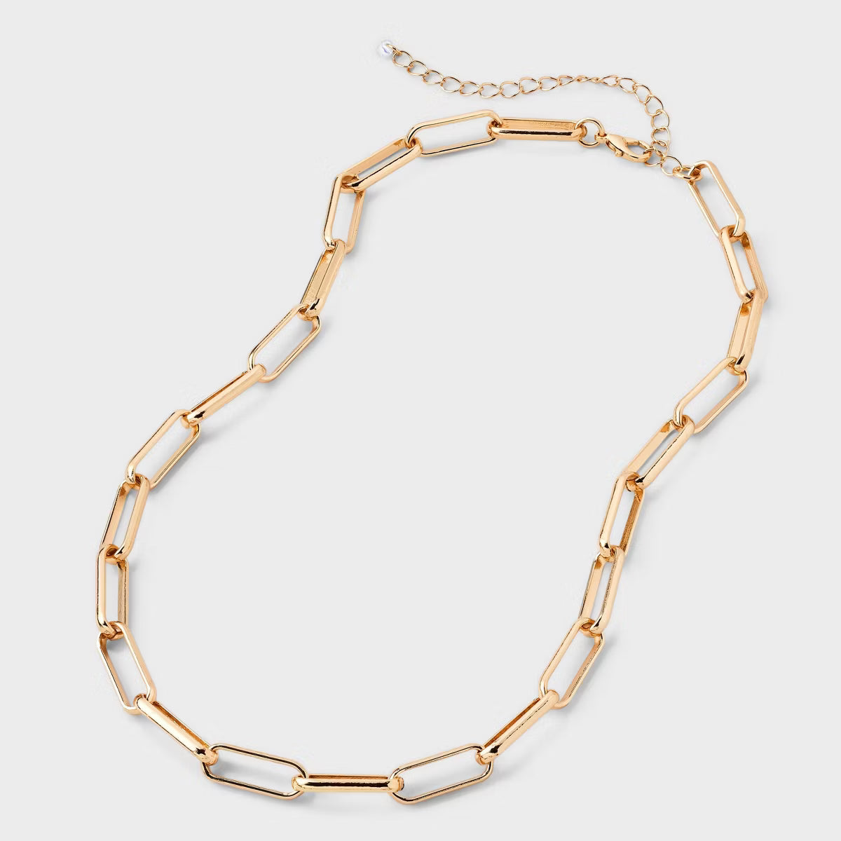 Gold chain necklace on a light gray background
