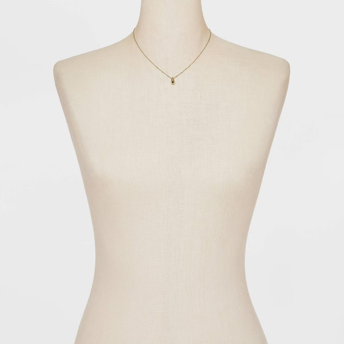 Mannequin wearing a gold necklace on a white background