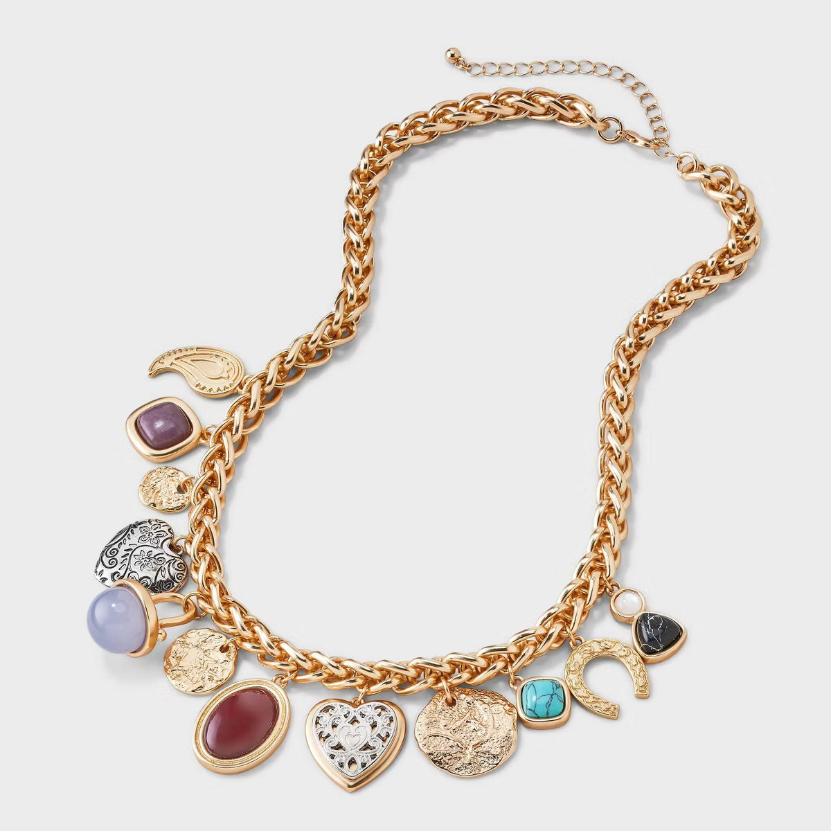 Gold necklace with various charms on a light gray background