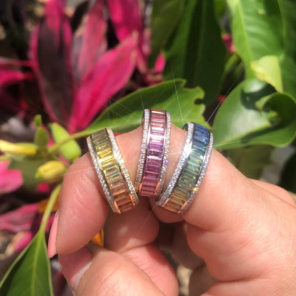 Three colorful rings on a finger with a blurred plant background