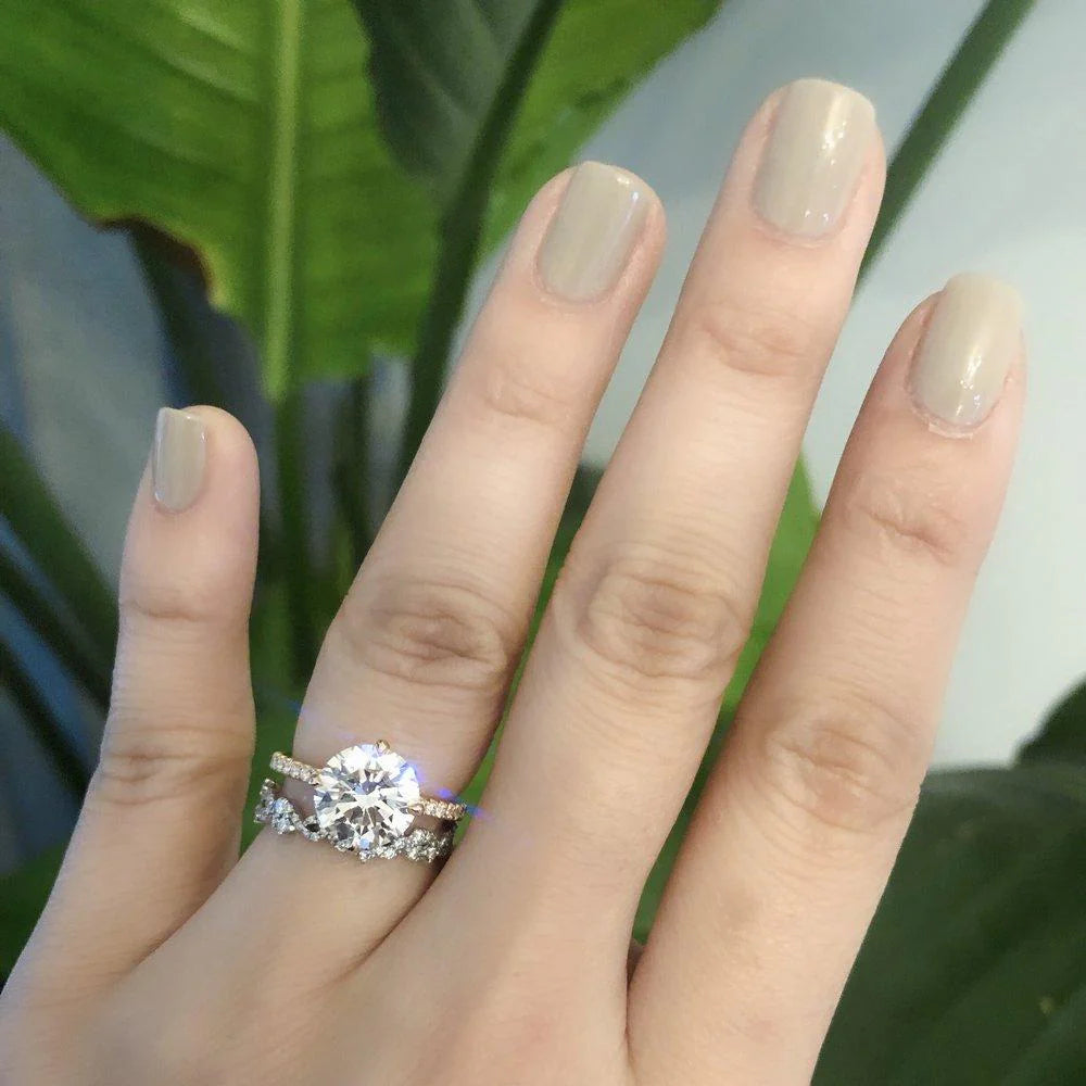 Hand wearing a diamond ring with a blurred green leaf background