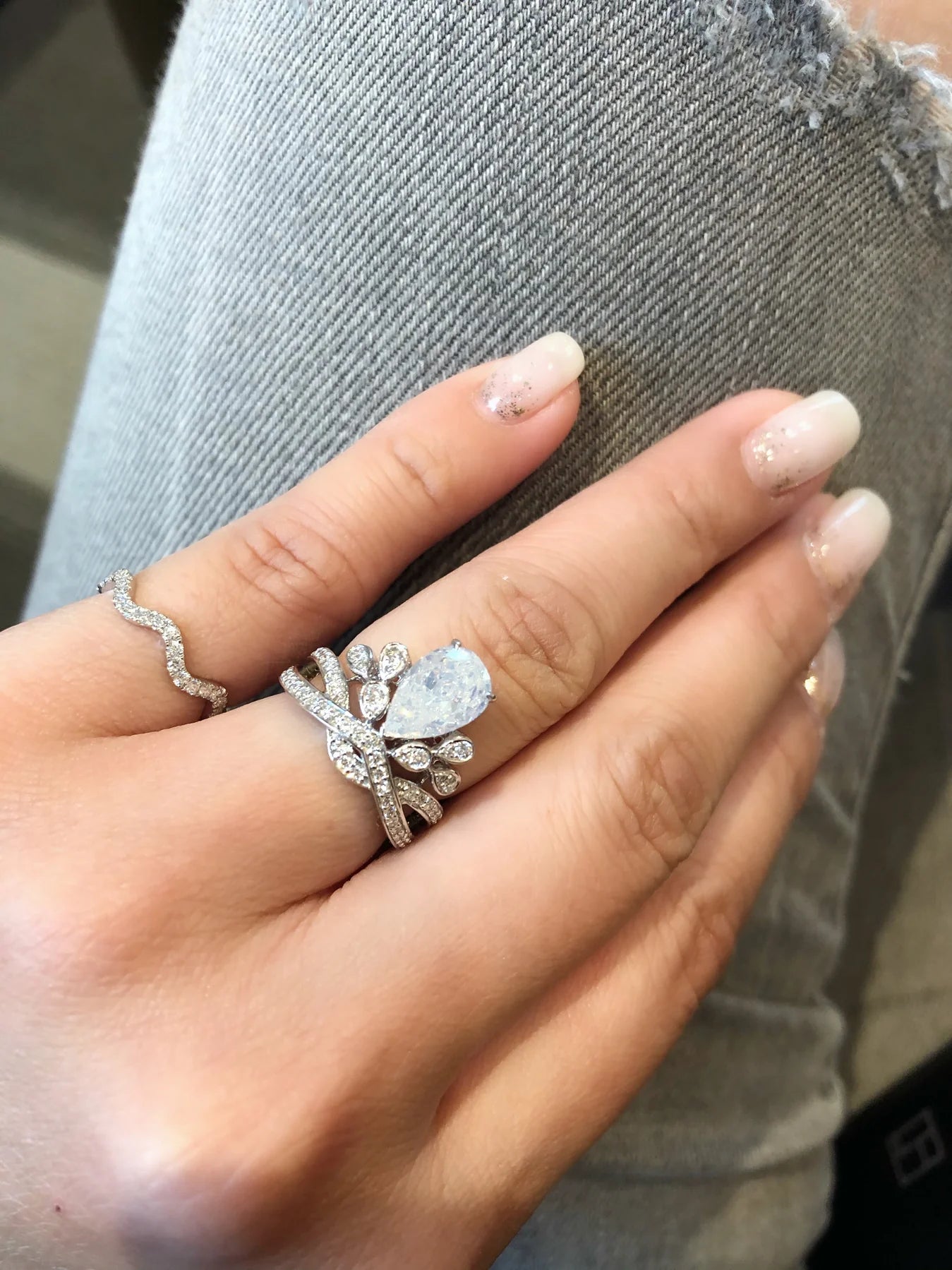 Hand wearing two silver rings with gemstones on a denim background