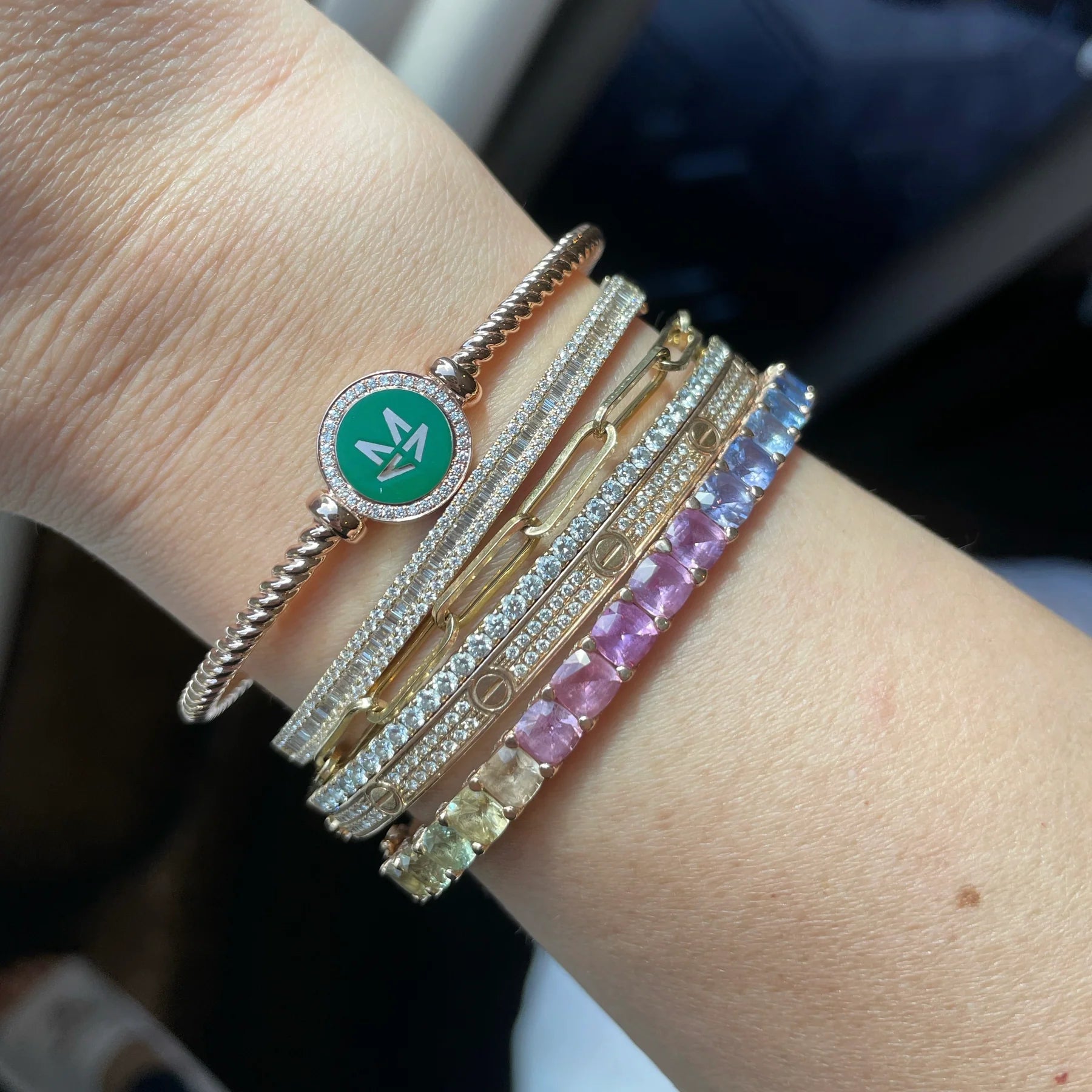 Close-up of a wrist wearing multiple bracelets with various designs and colors.