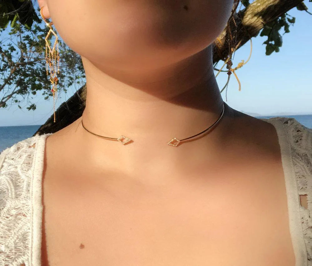 Necklace worn by a person with a scenic background of trees and water.