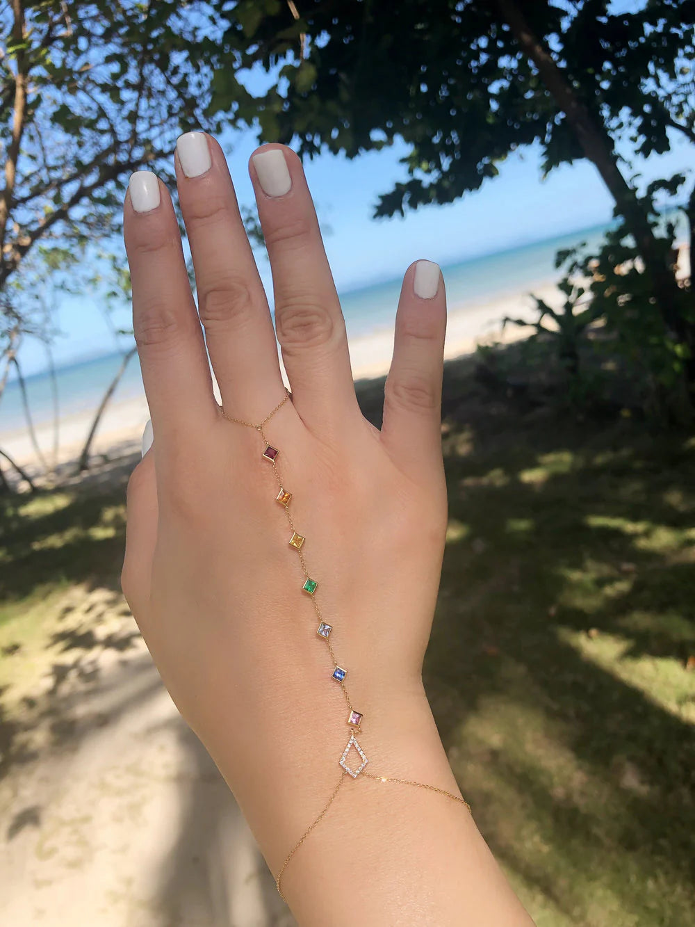 Hand wearing a delicate bracelet with a blurred beach background
