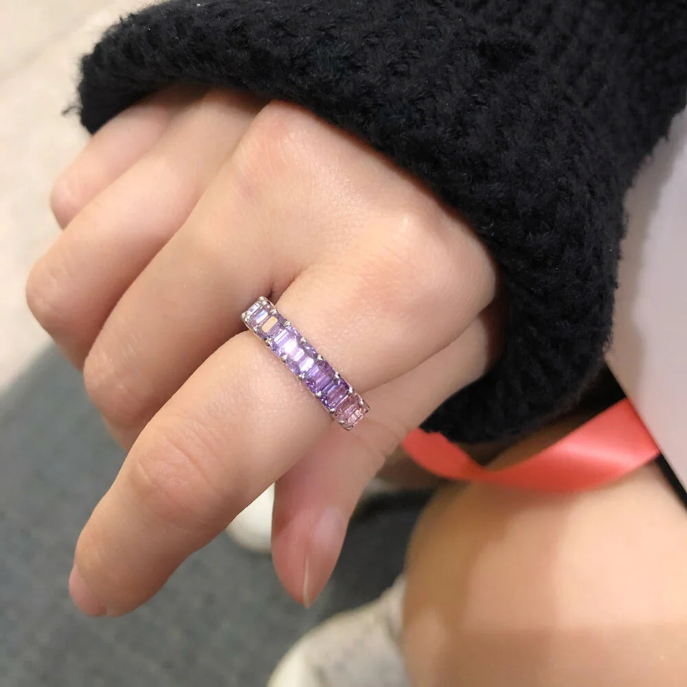 Hand wearing a ring with purple gemstones, blurred background