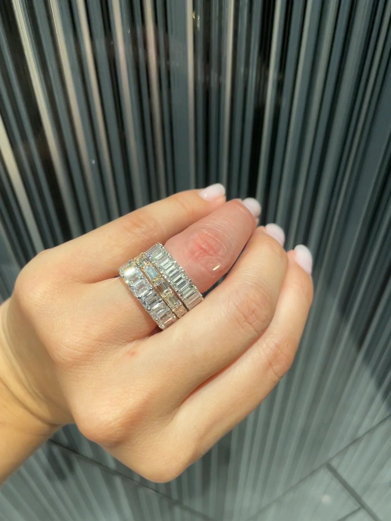 Horizontal emerald cut diamond eternity ring stacked with an engagement ring