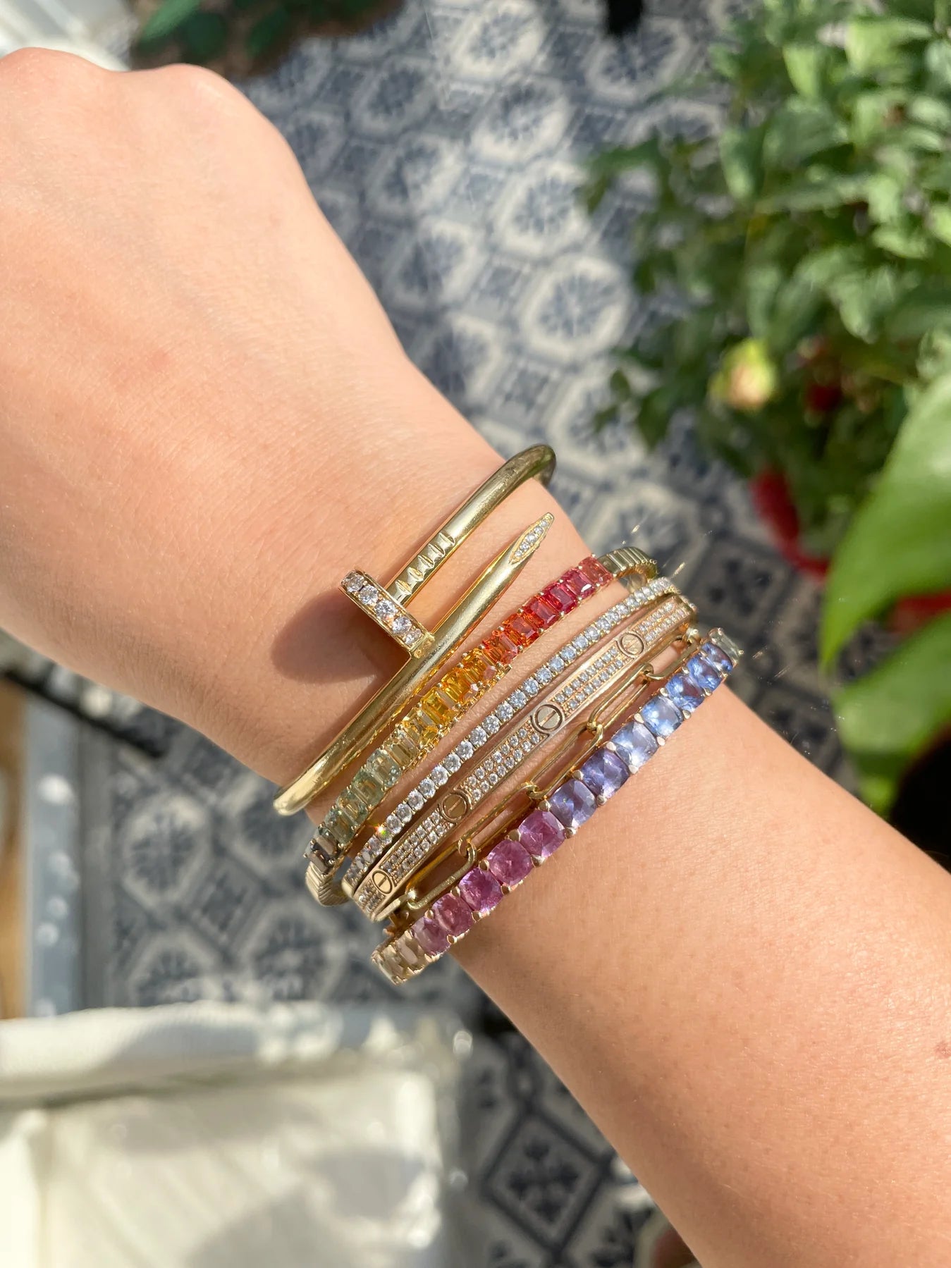 Close-up of a wrist wearing multiple colorful bracelets with a blurred outdoor background
